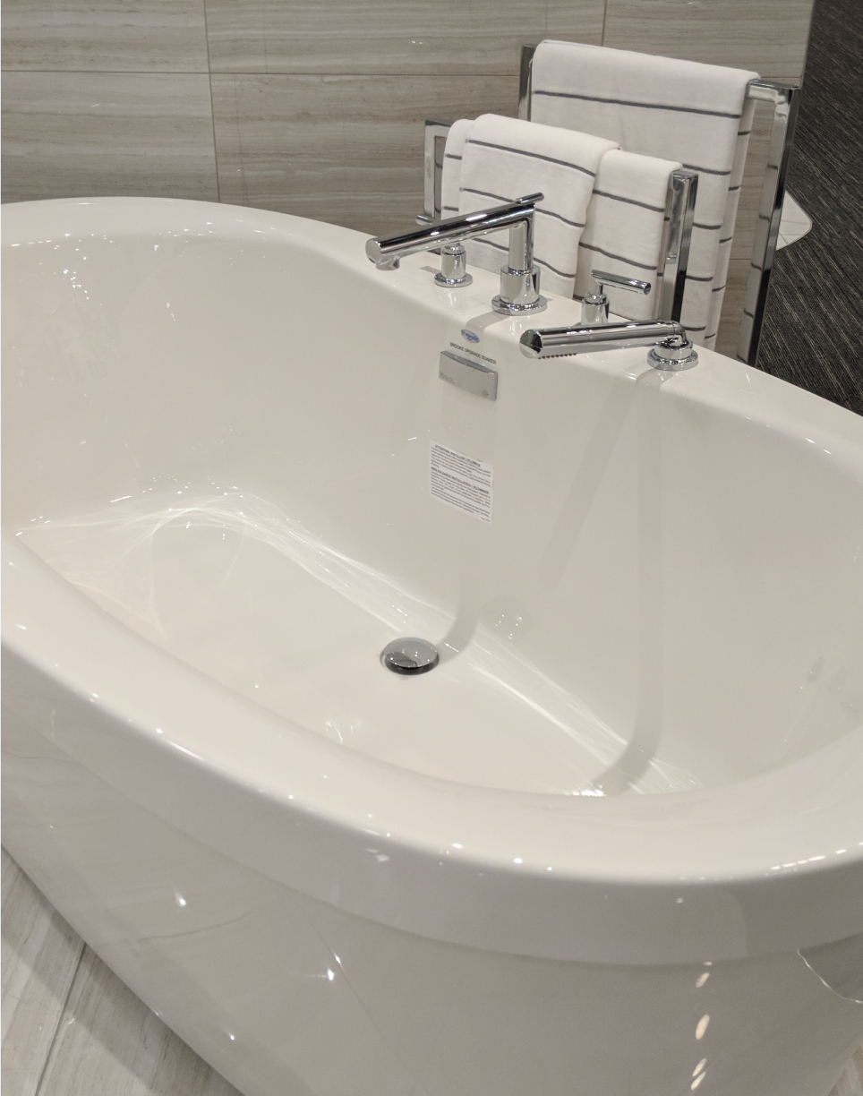 Image of large freestanding roman tub with stainless-steel taps available at ARISTA's Décor Studio.